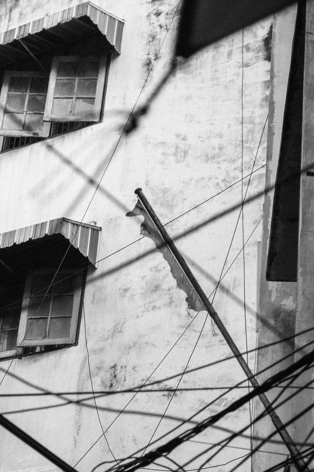 Photographic Art by Nick Sparks of a building with power lines and a worn down flag in Bangkok, Thailand. 