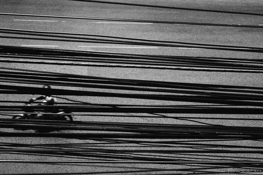 Photographic Art by Nick Sparks of a person riding a scooter with power lines in the foreground. 