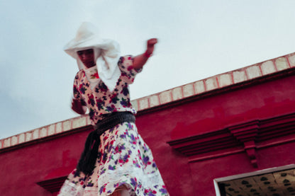 Photographic Art by Nick Sparks of a Oaxacan woman dancing in front of a magenta building. 