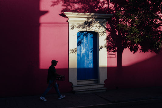 Photographic Art by Nick Sparks of a person walking by a pink wall and blue door. 