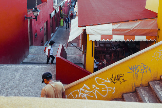 Photographic Art by Nick Sparks of two people walking candidly through a red and yellow market scene.