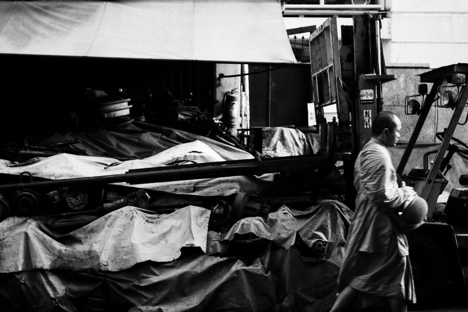 Photographic Art by Nick Sparks of a monk walking next to machinery. 