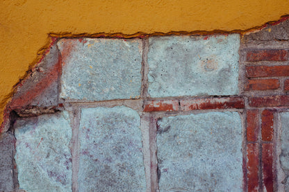 Photographic Art by Nick Sparks of blue stone revealed under a coat of cement and yellow paint. 