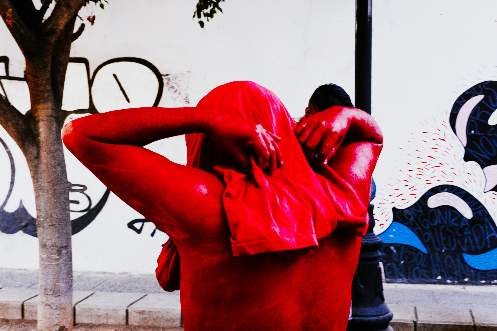 Photographic Art by Nick Sparks of a person painting himself red for a Mexican festival. 